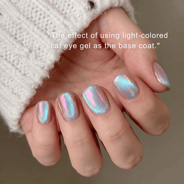 Nails with cat eye gel design held by a person wearing a white textured sleeve.