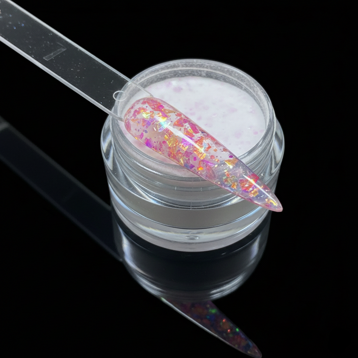 Jar of glittery nail powder with a nail next to it on a black background