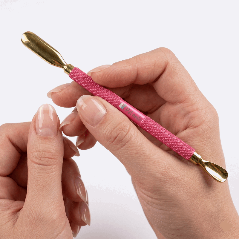 Pink crochet hook with gold end held in a hand against a white background