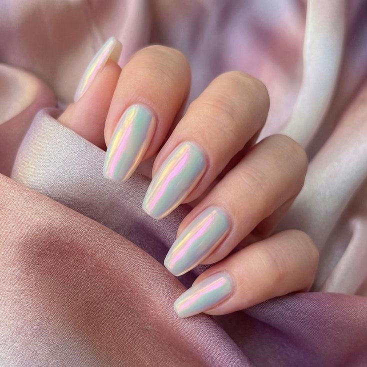 Close-up of a hand with pastel nail polish on a soft pink fabric background